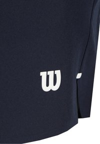 Tissu bleu marine avec un logo stylisé "W" blanc près de la couture et une petite fente sur le côté.
