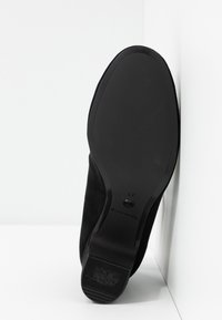 Suola in suede nero con una superficie liscia e strutturata. Presenta un tacco leggero e il nome del marchio in rilievo. Taglia indicata come 37.