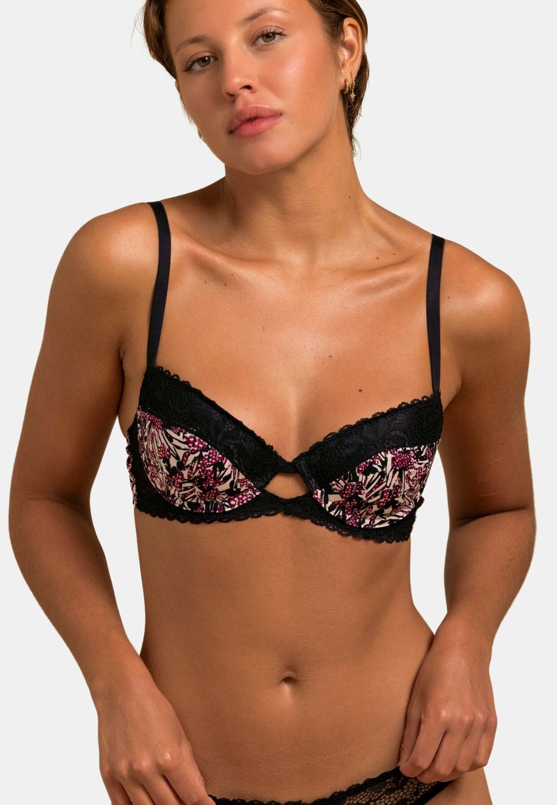 Lingerie noire et à motifs avec des designs floraux dans des teintes de rose et de crème, ornée de dentelle et avec des bretelles ajustables. Détail en clé à l'avant.