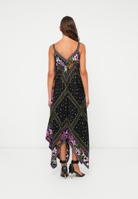 Vestido preto com um padrão floral geométrico, apresentando um decote nas costas em V, barra assimétrica e alças finas. Acentuado com pontos e desenhos coloridos.