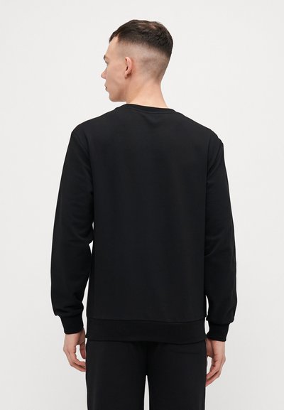 Sweatshirt noir à manches longues, texture lisse, col rond côtelé et ourlet. Conçu dans une coupe décontractée, vu de l'arrière.