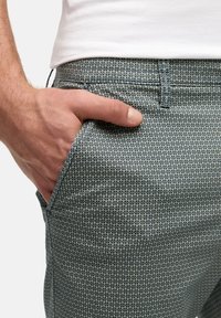 Pantaloni pentru bărbați, de culoare albastru deschis, cu un model geometric subtil. Dispune de un buzunar frontal și închidere cu nasture la talie.