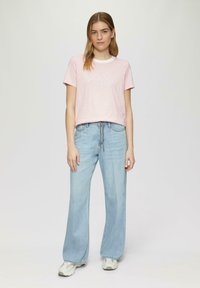 Lichtroze gestreepte t-shirt met "happy" tekst, gecombineerd met lichtblauwe wijde jeans en witte sneakers. Eenvoudig, casual ontwerp in zachte materialen.