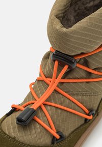Oliven grøn ankelstøvle med en tekstureret overdel, elastiske orange snørebånd og sorte hardware-detaljer. Blød indvendig foer synligt.