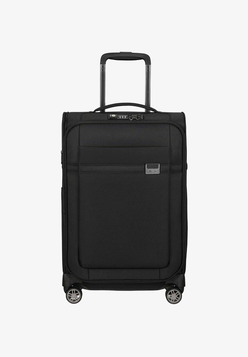 Valise souple noire avec poche avant, poignée rétractable, verrou à combinaison et quatre roues multidirectionnelles sur fond blanc.