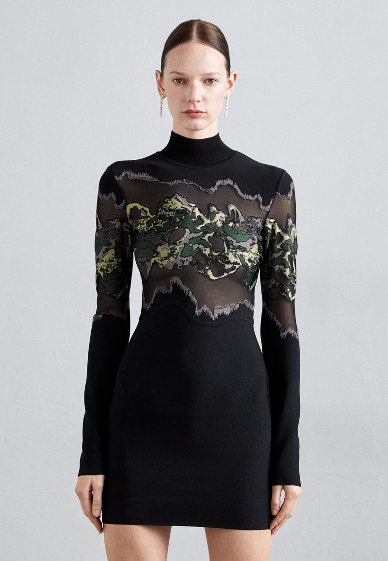 Black dress featuring a high neck, long sleeves, and a sheer panel with a green and black camouflage pattern across the chest.
