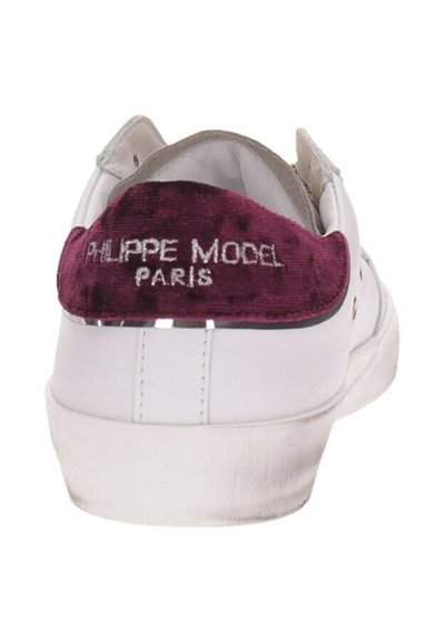 Baskets blanches avec un accent en velours violet au talon et une broderie argentée portant "Philippe Model Paris". Texture lisse et design bas.