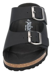 Svart slip-in sandal med två justerbara metallspännen, korkfotbädd och gummisula. Slätt material med öppen tådesign.