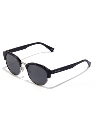 Black sunglasses with round lenses and a thin silver wire frame. Features a bold brow bar and sleek black plastic temples.