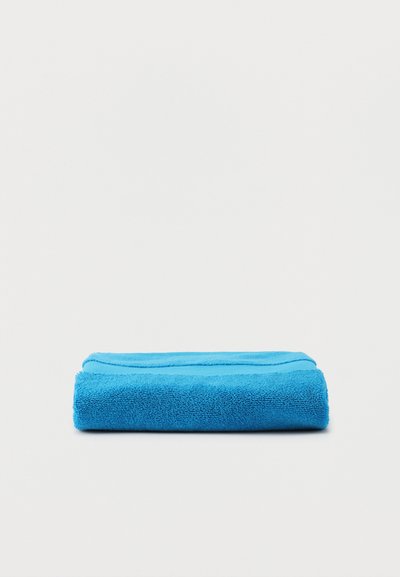 Πτυσσόμενο φωτεινό μπλε πετσέτα με υφή στην άκρη, τοποθετημένο σε απλή λευκή επιφάνεια.