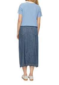 Blauw-wit gestreepte top met korte mouwen, gecombineerd met een lange spijkerrok met rafelrand en twee achterzakken. Gemaakt met lichte schoenen.