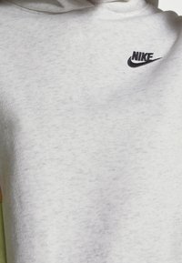 Felpa con cappuccio grigio chiaro con tessuto morbido e strutturato. Presenta il logo Nike nero sul petto. Nessun motivo o dettaglio hardware visibile.