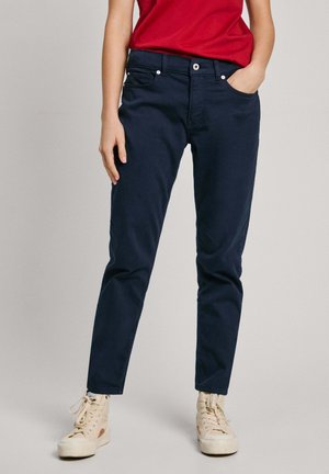 Tamsiai mėlynos spalvos džinsai, pagaminti iš medvilnės mišinio, turintys siaurą siluetą, penkias kišenes ir subtilius siuvimo akcentus.