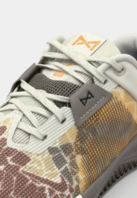Sneaker featuring a textured, multicolor mesh upper in shades of gray, beige, and orange. Includes lacing system and logo accent.