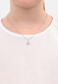 Collar de plata esterlina con un colgante de mariposa que presenta acentos rosas y azules, reposando sobre una camiseta blanca lisa.