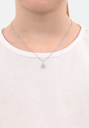 Sterling-Silber-Halskette mit einem Schmetterlingsanhänger, der rosa und blaue Akzente aufweist, auf einem schlichten weißen Shirt liegend.