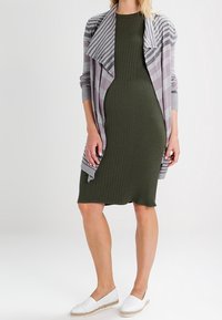 Olive green ribbed dress paired with a gray and lavender striped cardigan. White espadrille shoes complete the look.