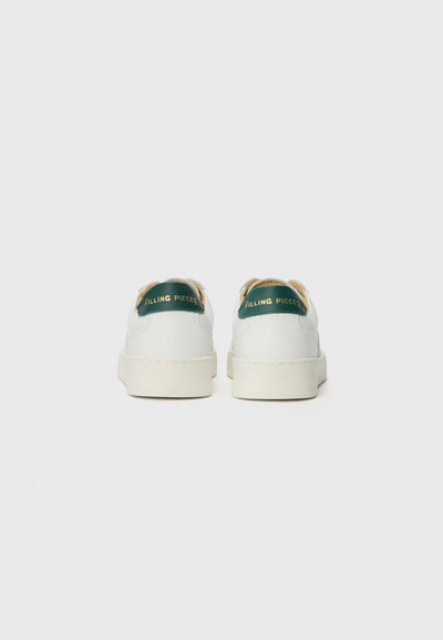 Weiße Leder-Sneaker mit runder Zehenpartie, dicker Sohle, grünem und goldenem Logo an der Ferse und beigen Akzenten entlang des Kragens.