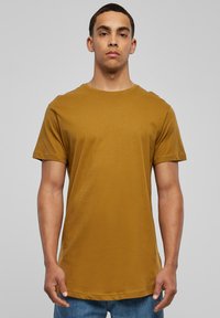 Sennepsgul bomulds T-shirt med rund hals og korte ærmer. Lige kant ved taljen, glat tekstur og minimalistisk design.
