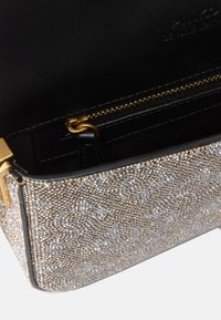 Borsa scintillante in argento e oro con interno in pelle nera liscia, dotata di una tasca con zip e dettagli in hardware dorato.