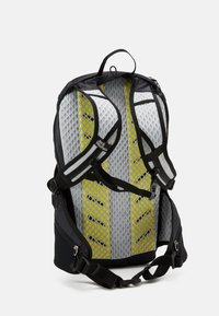 Sac à dos avec un extérieur noir et un dos en mesh gris, orné d'accents jaunes. Comprend des bretelles rembourrées et une poignée de transport sur le dessus.