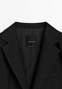 Zwarte op maat gemaakte blazer met inkeping revers en borstzak, binnenetiket toont "Massimo Dutti, gemaakt in Portugal."
