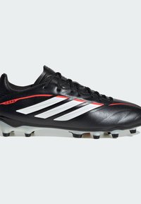 Schwarzer Adidas Copa Fußballschuh mit weißen Streifen, roten Akzenten, Schnürverschluss und profilierten Stollen auf der Sohle für festen Untergrund.