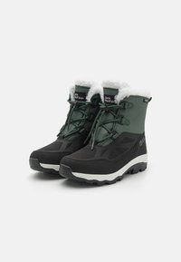 Czarne i zielone wodoodporne zimowe buty z białym sztucznym futerkiem, sznurowany design, teksturowany materiał oraz solidna podeszwa zapewniająca przyczepność.