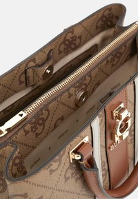 Sac à main à motifs marron avec quincaillerie dorée, fermeture éclair, et un mélange d'accents marron et crème, avec une finition lisse et texturée.