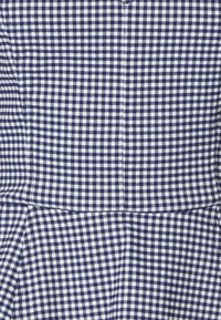 Tela a rayas en azul marino y blanco con un patrón de rejilla, que presenta pequeños cuadrados, superficie texturizada y detalles de diseño plegados.