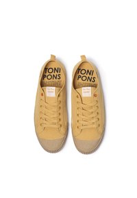 Žute platnene tenisice s teksturiranim gumenenim potplatom, s vezicama i logotipima "TONI PONS" i "INSTINT" na jeziku.