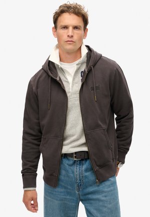 Dark gray zip-up hoodie with a front pocket, cotton fabric, drawstring hood, paired with a light gray collared shirt and blue jeans.