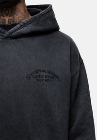 Felpa nera con cappuccio realizzata in tessuto morbido. Presenta un testo in rilievo che recita "GOOD FOR NOTHING BRITISH ATELIER EST 2011" sul petto.