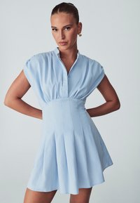 Svijetloplava haljina s ovratnikom, kratkim rukavima i oblikovanim korzetom. Ima nabore na suknji i mekanu teksturu tkanine.