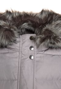 Puffjacka i ljusgrå, med huva i konstpäls i mörkgrå. Tre silverfärgade tryckknappar och quiltad textur synlig på framsidan.