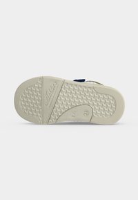 Semelle d'une chaussure d'enfant avec motif de grip texturé, nom de marque "Aldila's," et taille 21 indiquée sur une semelle en caoutchouc clair.