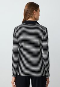 Czarny i biały pasiasty longsleeve z prążkowanym wzorem i jednolitym czarnym kołnierzykiem; dopasowany krój, widok z tyłu.