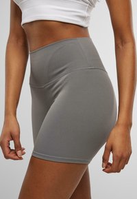 Pantalones cortos deportivos grises de cintura alta, fabricados con un material elástico y costuras planas para mayor comodidad. Cuentan con una textura suave y un diseño ajustado.