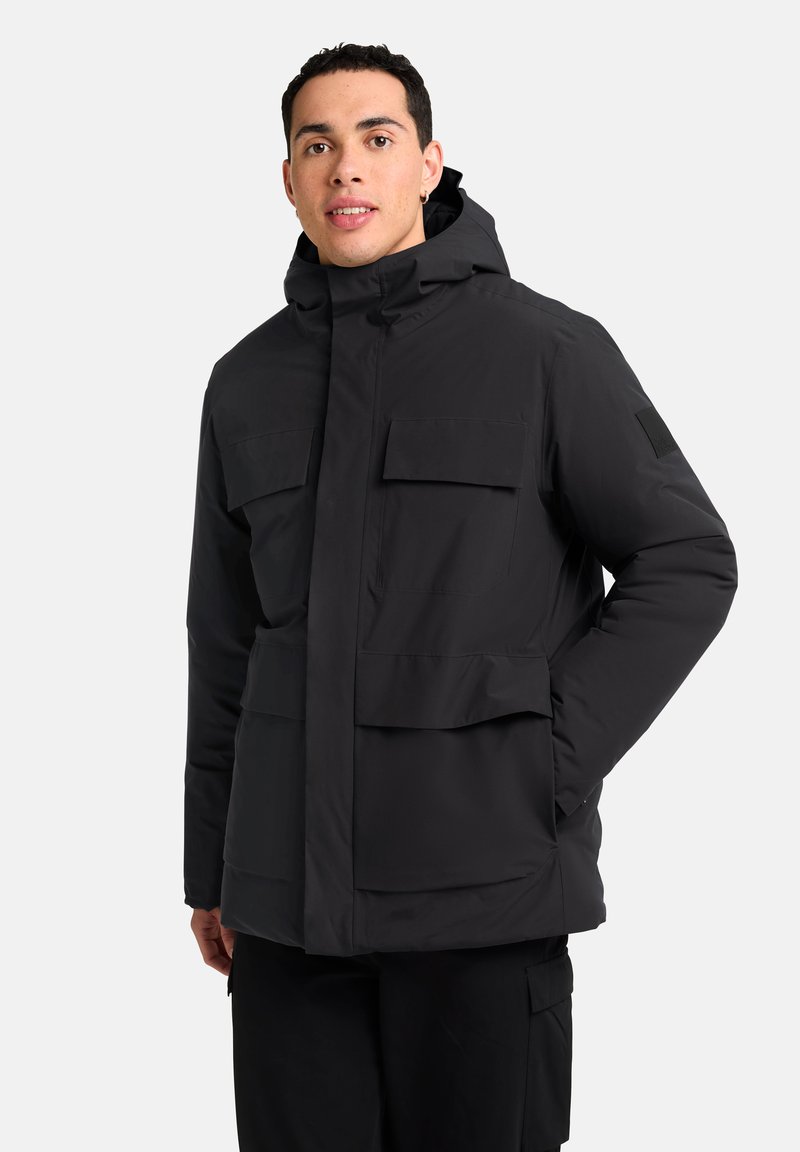 Veste isolante noire avec capuche, dotée de plusieurs poches avant, d'une fermeture éclair et d'une texture lisse et élégante.