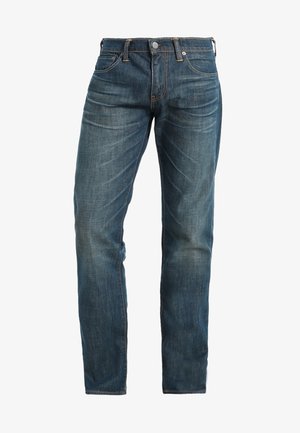 Vaqueros de mezclilla azul oscuro con corte recto, que presentan detalles de desgaste y de arrugas. Estilo clásico de cinco bolsillos y sutiles acentos de costura.