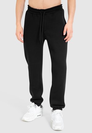 Sorte sweatpants med snørebånd i taljen, ribbede manchetter og glat stof. Har sømme langs benene for ekstra design Detaljer.