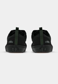 Crne tenisice s gornjim dijelom od teksturirane tkanine, zelenim povlačenjem na peti i gumenenim potplatom. Imaju suptilni brending i čvrstu izradu.