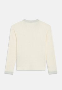 Hvit strikket genser med ribbestruktur, V-hals og sølvfargede manchetter. Designet har lange ermer og en cropped lengde.