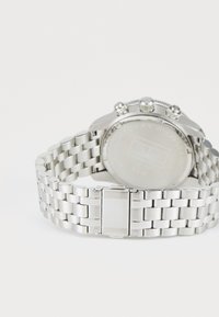 Orologio in acciaio inossidabile argentato con bracciale a maglie, quadrante rotondo, indicatori cronografici e fondo cassa liscio. Branding inciso visibile.