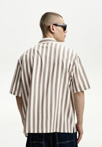 Short-sleeved button-up shirt featuring vertical brown and white stripes, lightweight fabric, relaxed fit, and a classic collar design.