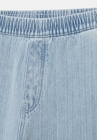 Jasnoniebieski dżinsowy materiał o wzorze jodełki oraz elastyczny pas z widocznym przeszyciem.