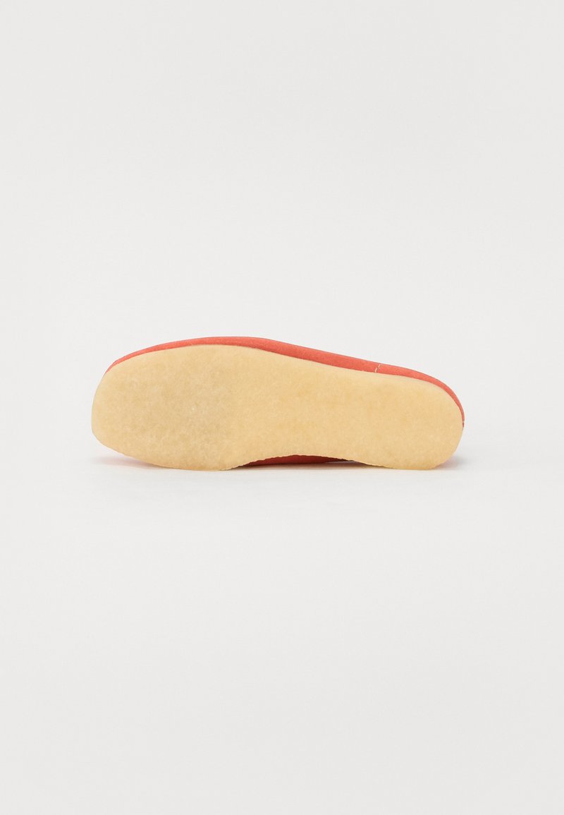 Zapato rojo con un material superior liso y una suela de goma beige clara, que presenta una forma redondeada y un diseño minimalista sin acentos visibles.