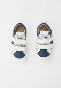 Hvite og marineblå sneakers med mesh og lærmaterialer, doble borrelåser, avrundet tå og en teksturert gummisåle. Rød aksent på hælen.