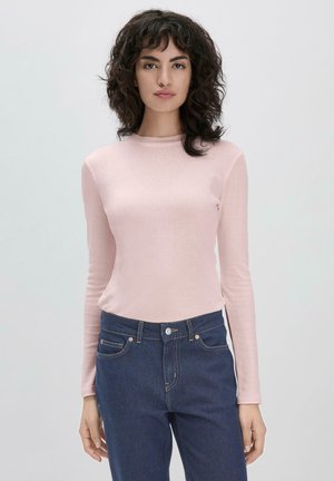 Hellrosa Langarmoberteil aus weichem Stoff mit rundem Ausschnitt. Kombiniert mit dunkelblauen Jeans, die vorderen Taschen sichtbar.