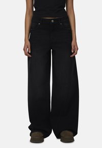 Zwarte denim jeans met wijde pijpen, voorzakken, metalen knoopsluiting en subtiele stikdetails. Gemaakt van zachte, duurzame stof.